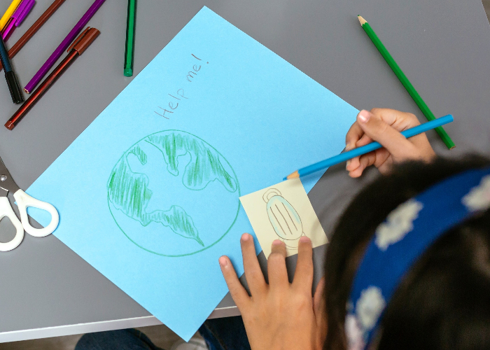 Child drawing Earth on blue paper