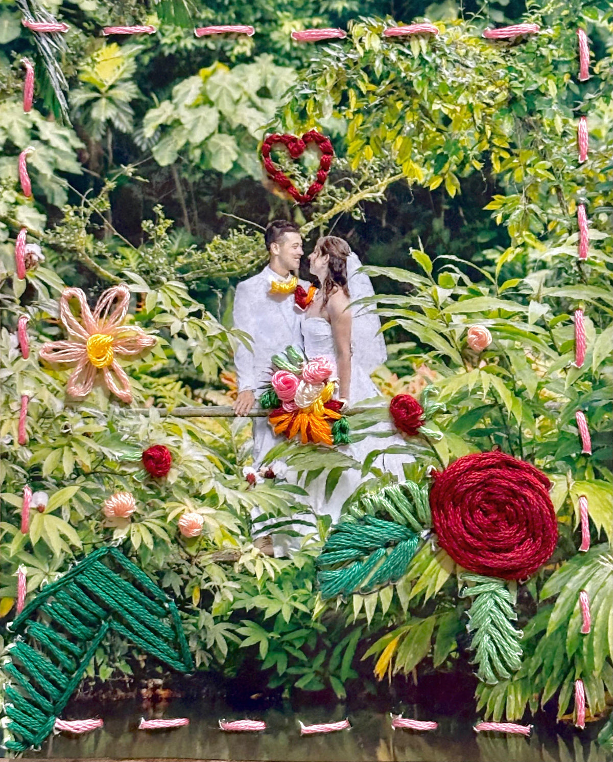 A couple sits in a lush garden surrounded by oversized decorative flowers and pink hanging ornaments.