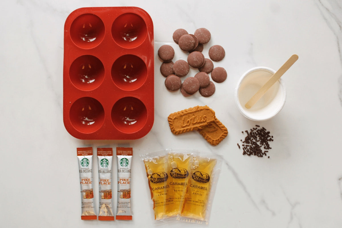 Coffee bomb kit: a red silicone mould, chocolate discs, instant coffee sachets and toppings