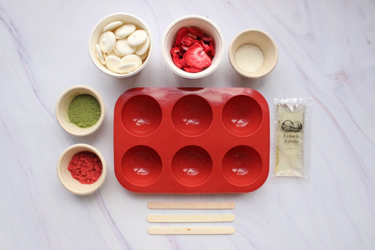 Matcha bomb kit: red silicone mould, white chocolate buttons, matcha powder and freeze-dried strawberry