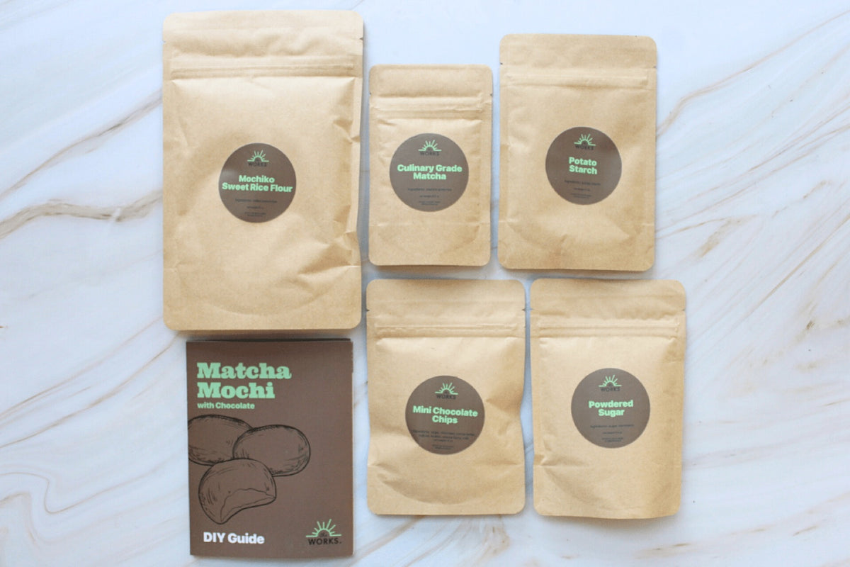 Mochi kit sachets of matcha, sweet rice flour and sugar laid out on marble