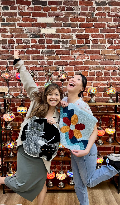 Two friends holding tufted rugs