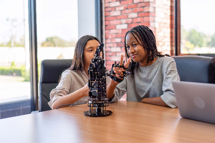 Two students testing robotic hand with sensor glove