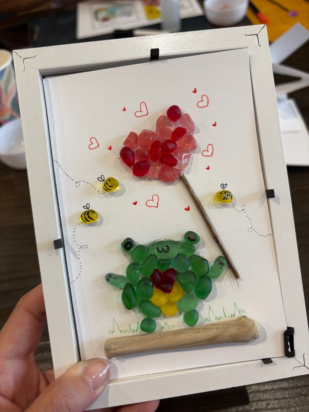 Date workshop at KraftStories Hawaii, sea glass art frame with a frog holding a heart shape balloon.