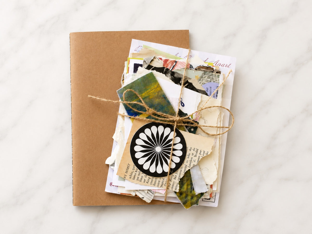 Kraft notebook with a bundle of vintage papers and a paper rosette tied on top