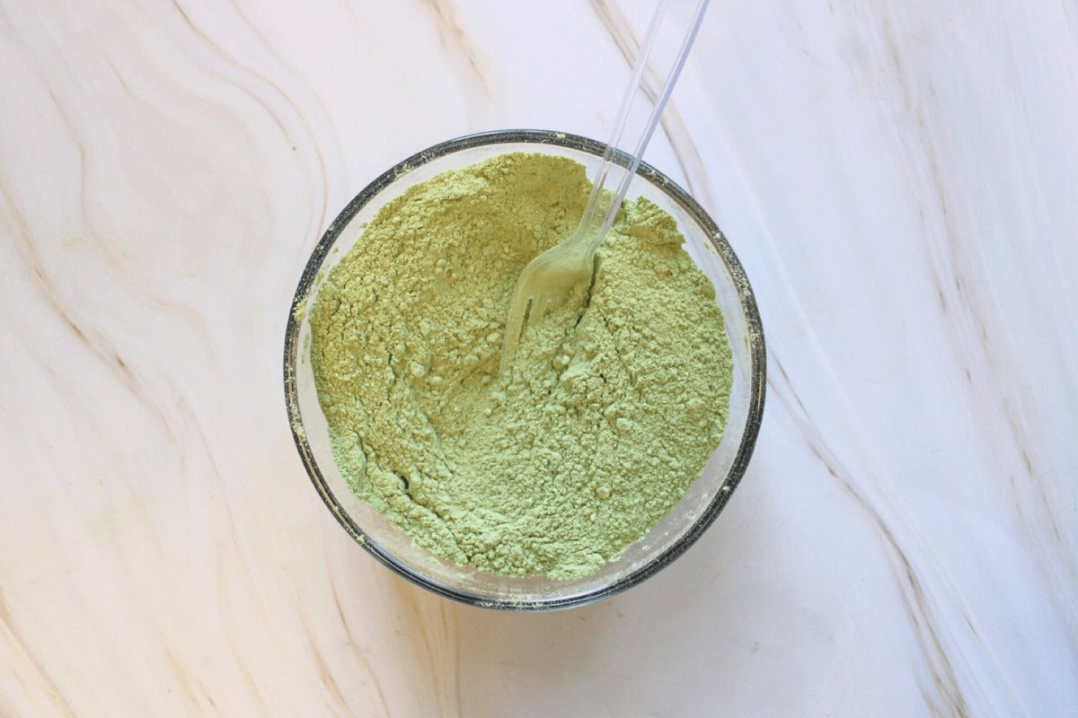 Glass bowl of bright green matcha powder being whisked