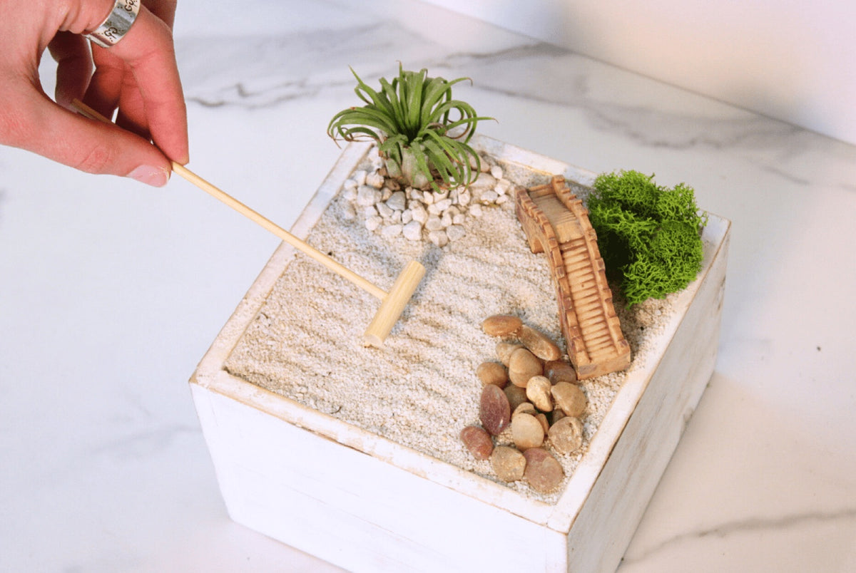 Hand raking lines into the white sand of a zen garden