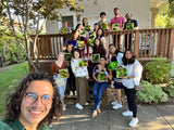 A group of people posing, including a man with glasses and a woman holding a craft picture, likely at a KraftStories workshop.