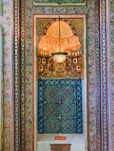 An ornate doorway with a chandelier, featuring intricate blue and green tiles and a marble sign, emphasizing artistic craftsmanship.