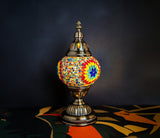 A colorful mosaic lamp with a vibrant shade on a table, showcasing intricate craftsmanship.