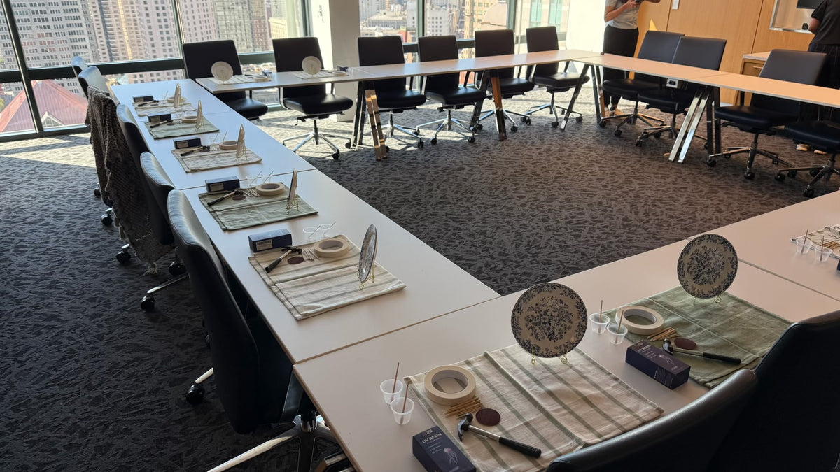 Conference room set up with craft supplies and place settings along long white tables.