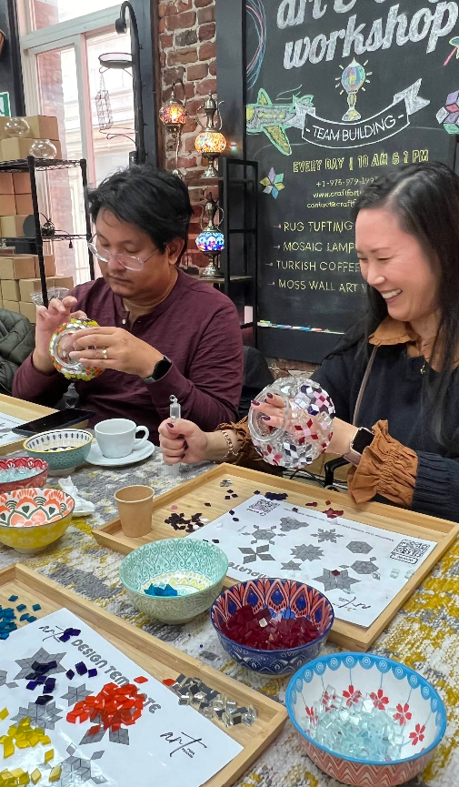 Two people crafting mosaic lamps