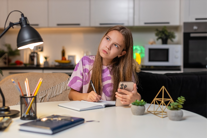 Girl thinking while writing in notebook