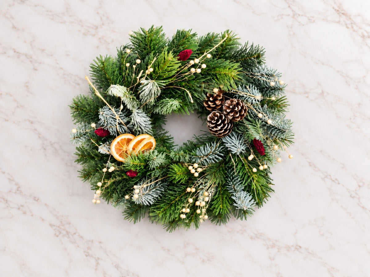 Completed evergreen wreath laid flat on a pale surface
