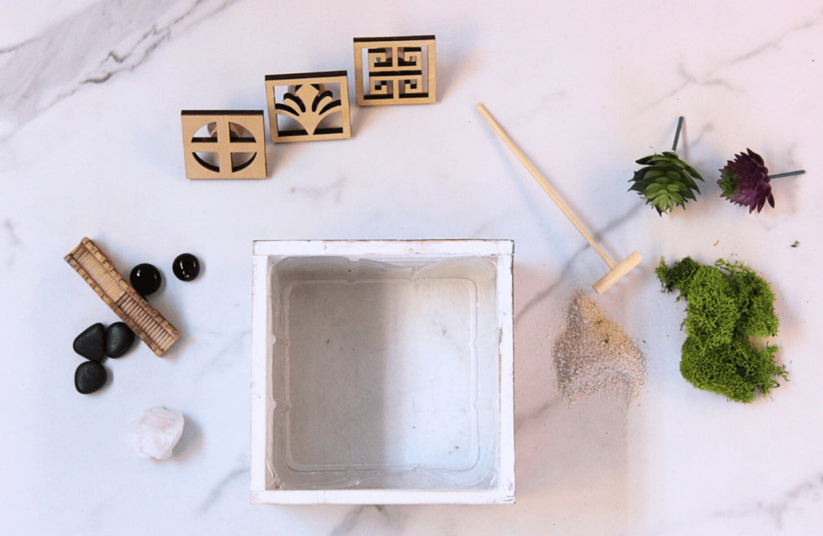 Zen garden kit: white tray, wooden stamps, black stones, moss and a miniature rake