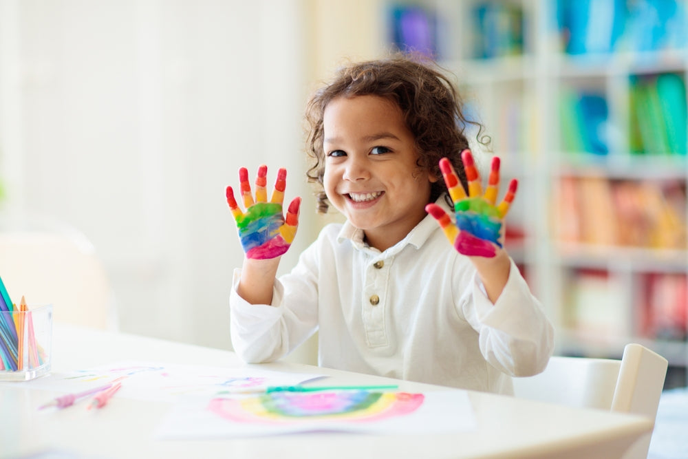 A smiling child with paint-covered hands