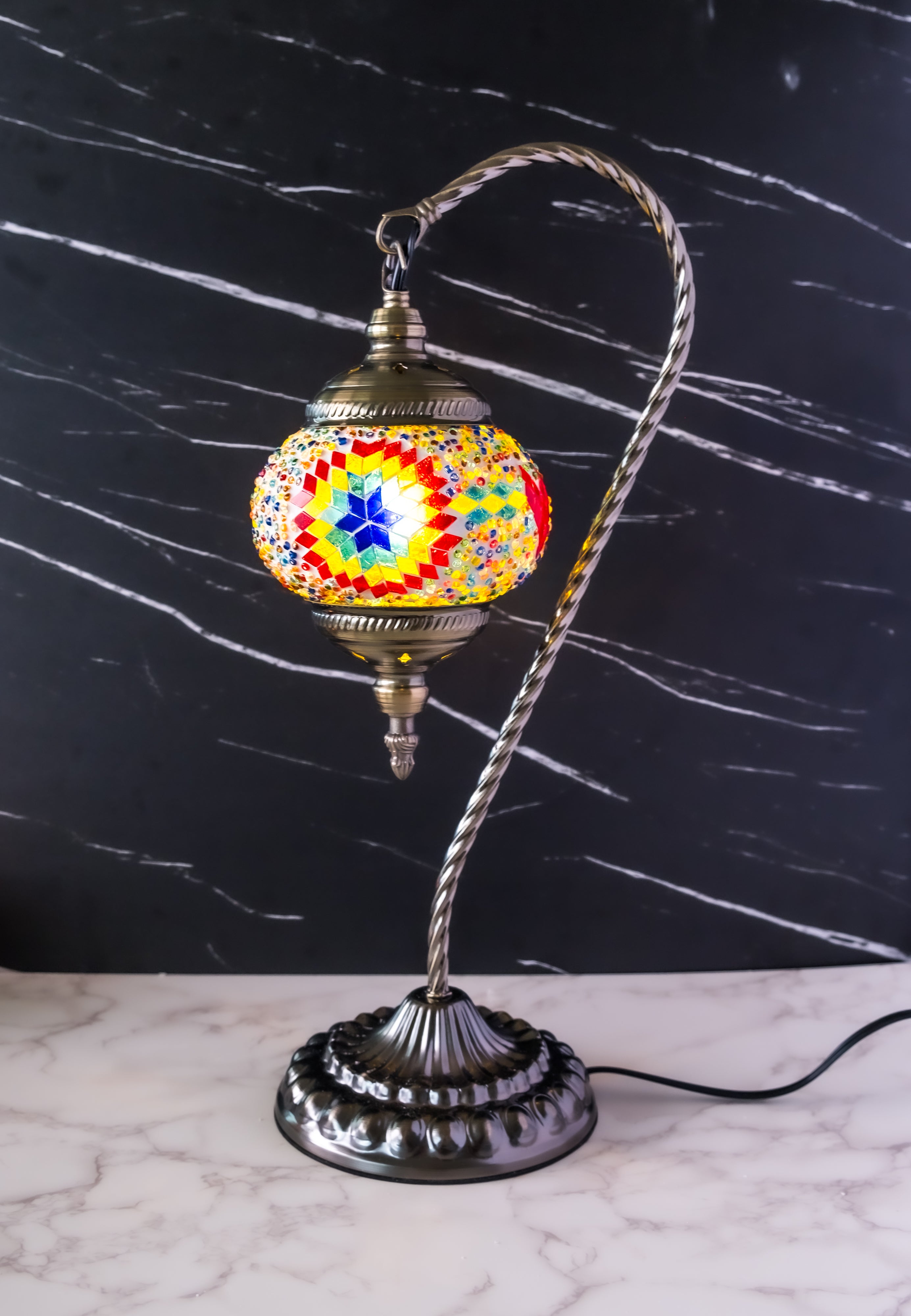 Colorful Turkish mosaic lamp with intricate pattern and gold-tone detailing, set against a dark marble background.