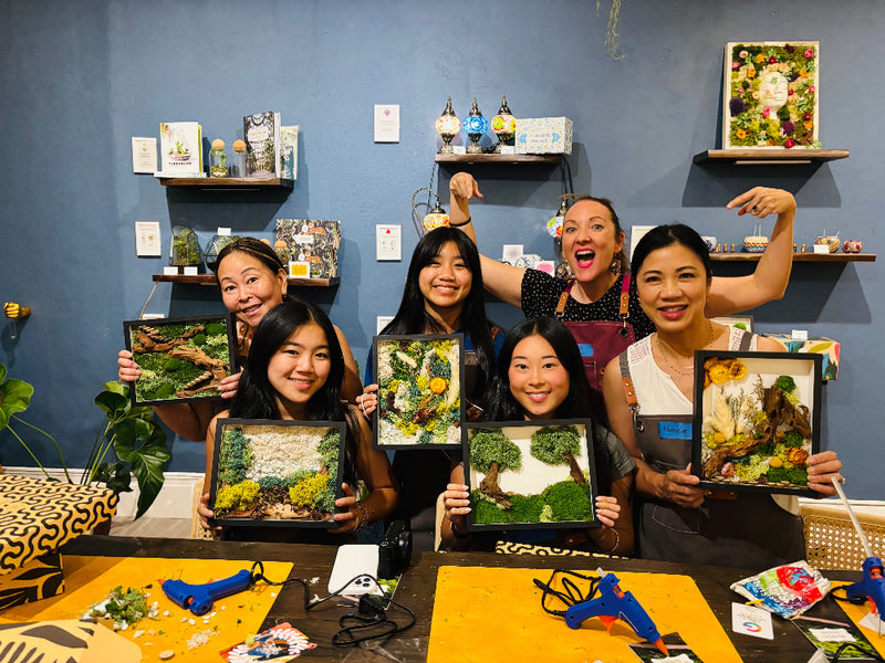 A group holding up the moss wall art frames they made at KraftStories.