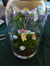 A completed terrarium featuring green plants inside a glass container, made during a virtual terrarium workshop for teams.